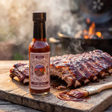 Nomad Chilli Co The BBQ Sauce bbq sauce — sticky glazed pork ribs off the barbecue with the bottle on a timber board