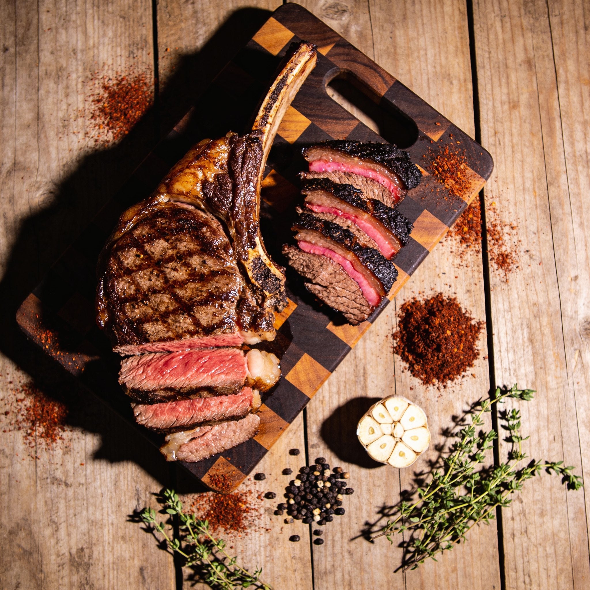 Plowboys Bovine Bold Rub on a sliced tomahawk steak and smoked brisket — beauty shot on butcher block
