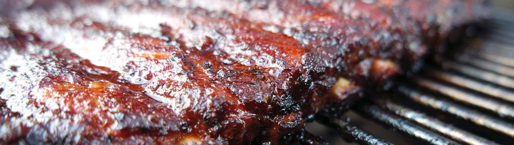 Hardcore Carnivore Red all-purpose BBQ rub beside juicy grilled pork chops and glazed chicken thighs with caramelised char marks
