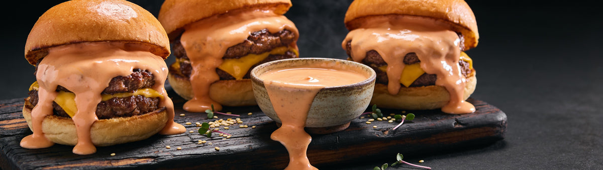 Republic Smash Sauce with smash burgers and glazed wings on a backyard picnic table