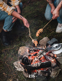 Road Trip Cooking by The Holy Kauw Company paperback cookbook — interior page of hotdogs on a stick over the fire