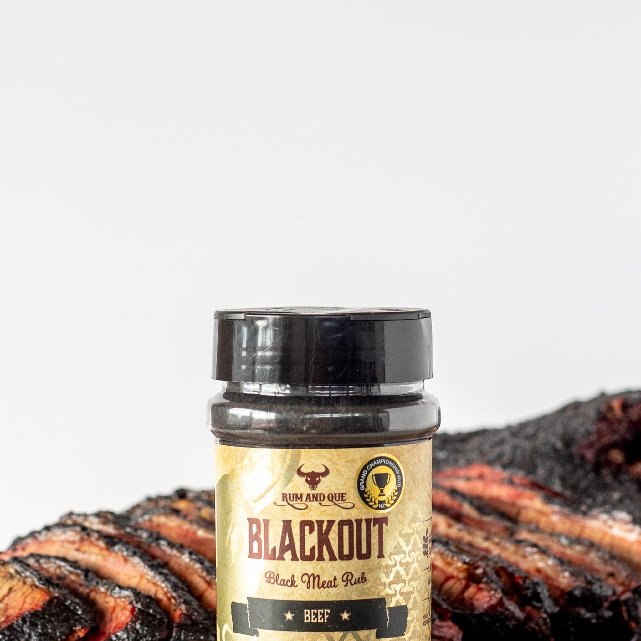 Rum and Que Blackout beef rub — sliced smoked brisket with a dark bark, shaker alongside
