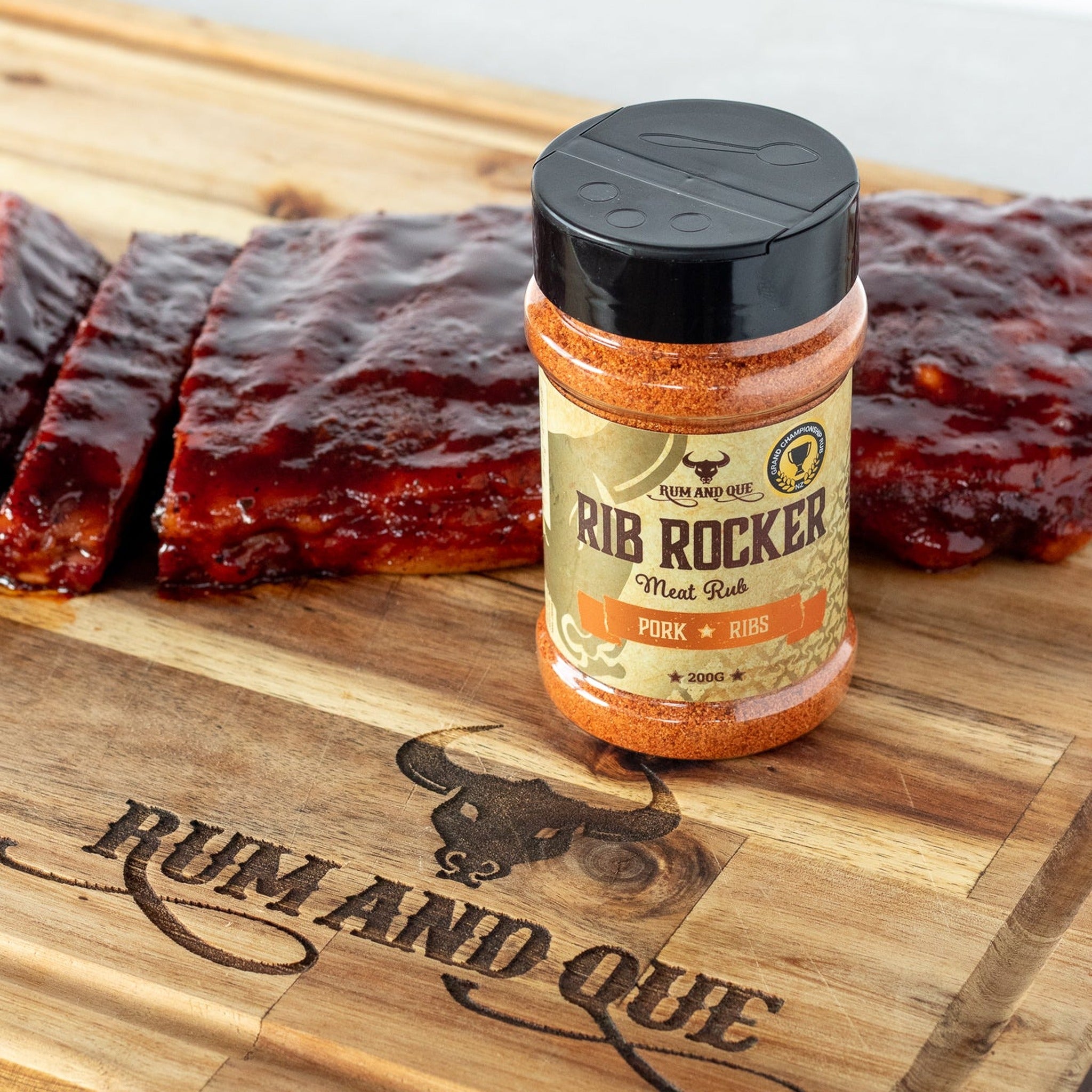 Rum and Que Rib Rocker pork rub — glazed pork ribs on a Rum and Que board with the shaker