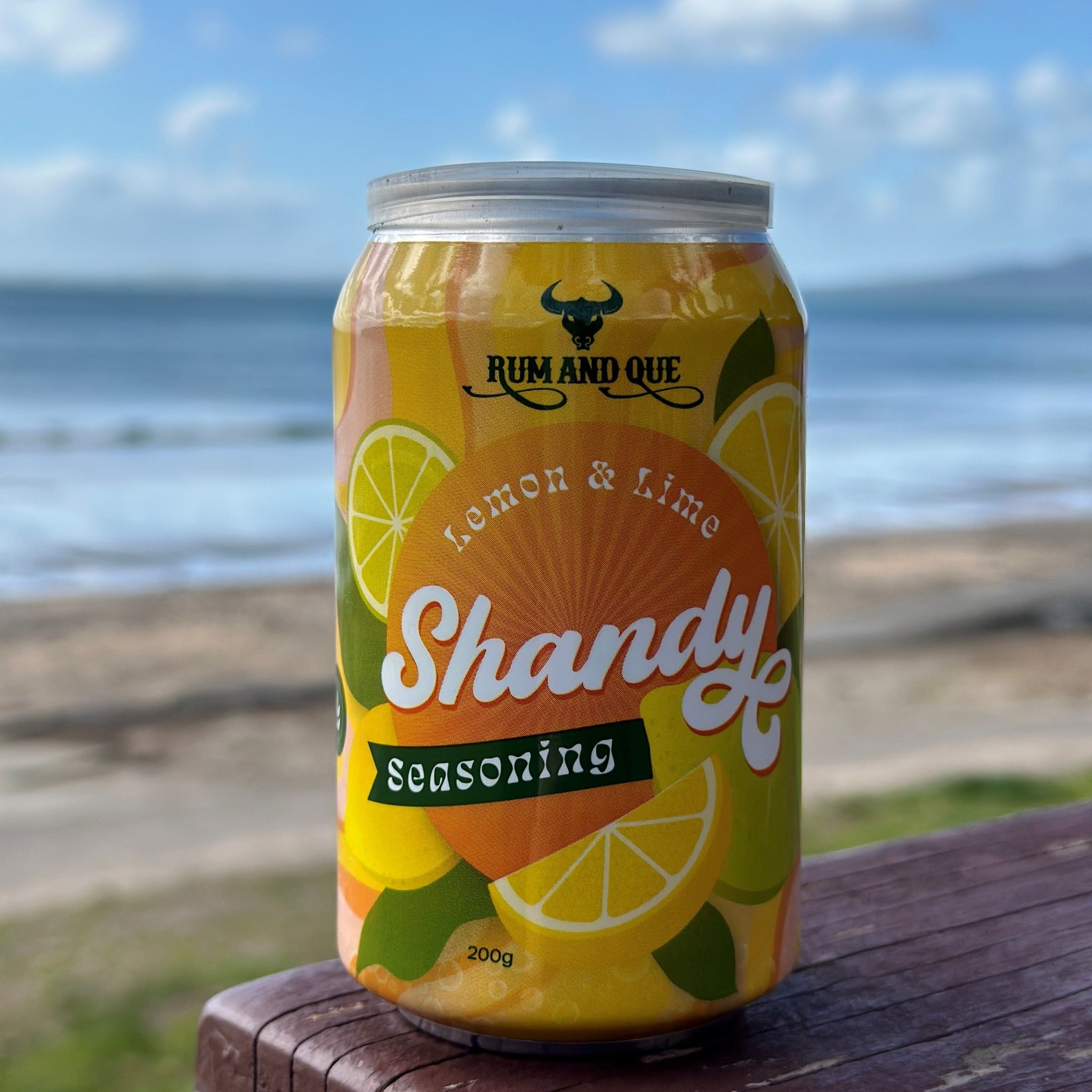 Rum and Que Shandy lemon-lime beer rub can on a beachside table