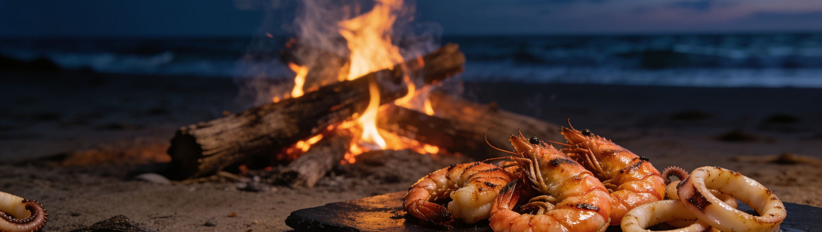 Stef the Maori Aquadesiac Surf Turf and Veggies Seasoning 220g banner — chargrilled prawns and calamari on a slate board beside a driftwood beach fire at dusk