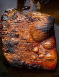 Stoked by Al Brown hardback cookbook — crackling-topped roast pork belly from the book's shoot