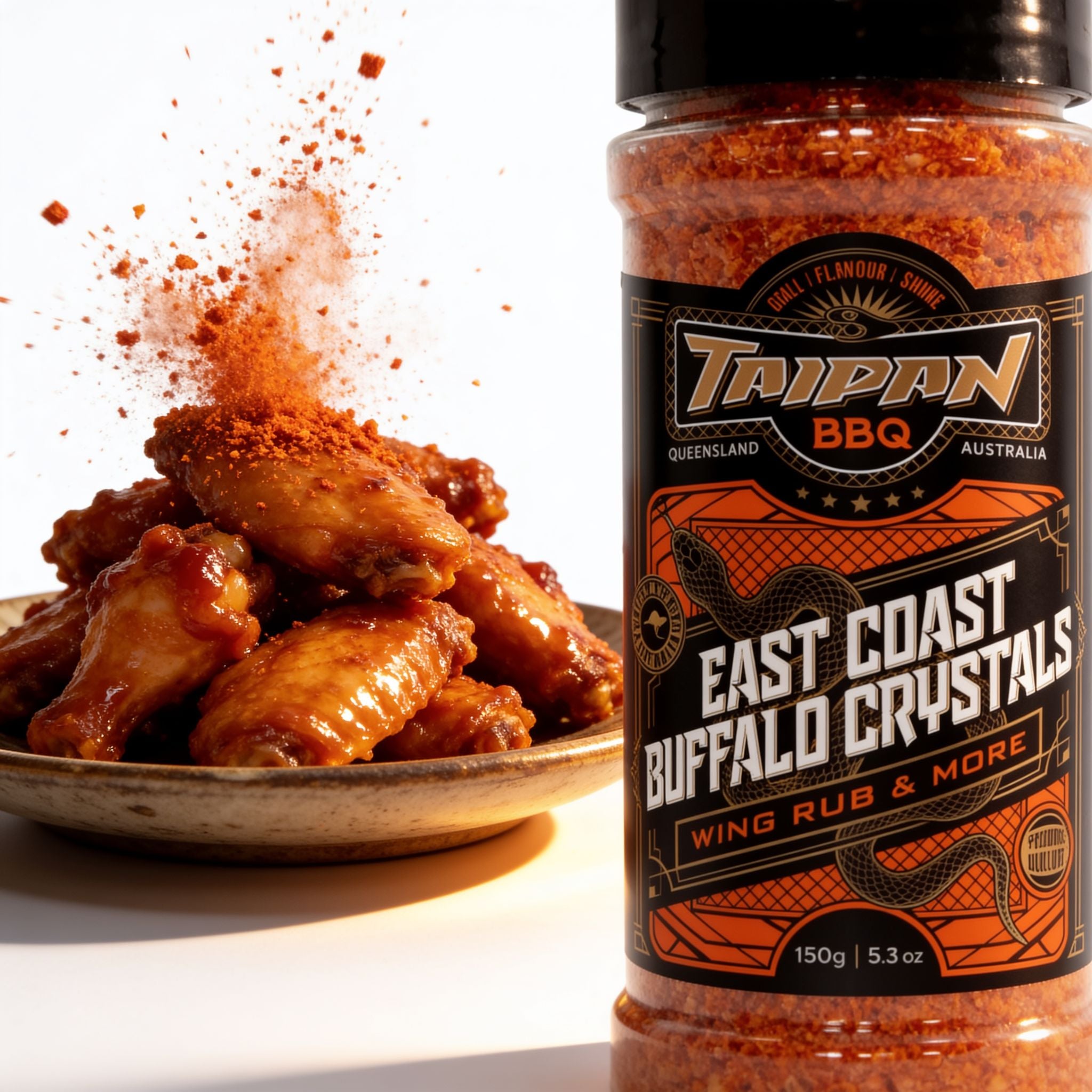 TAIPAN BBQ East Coast Buffalo Crystals buffalo wing seasoning 150g — action shot, seasoning granules exploding over a pile of glazed wings
