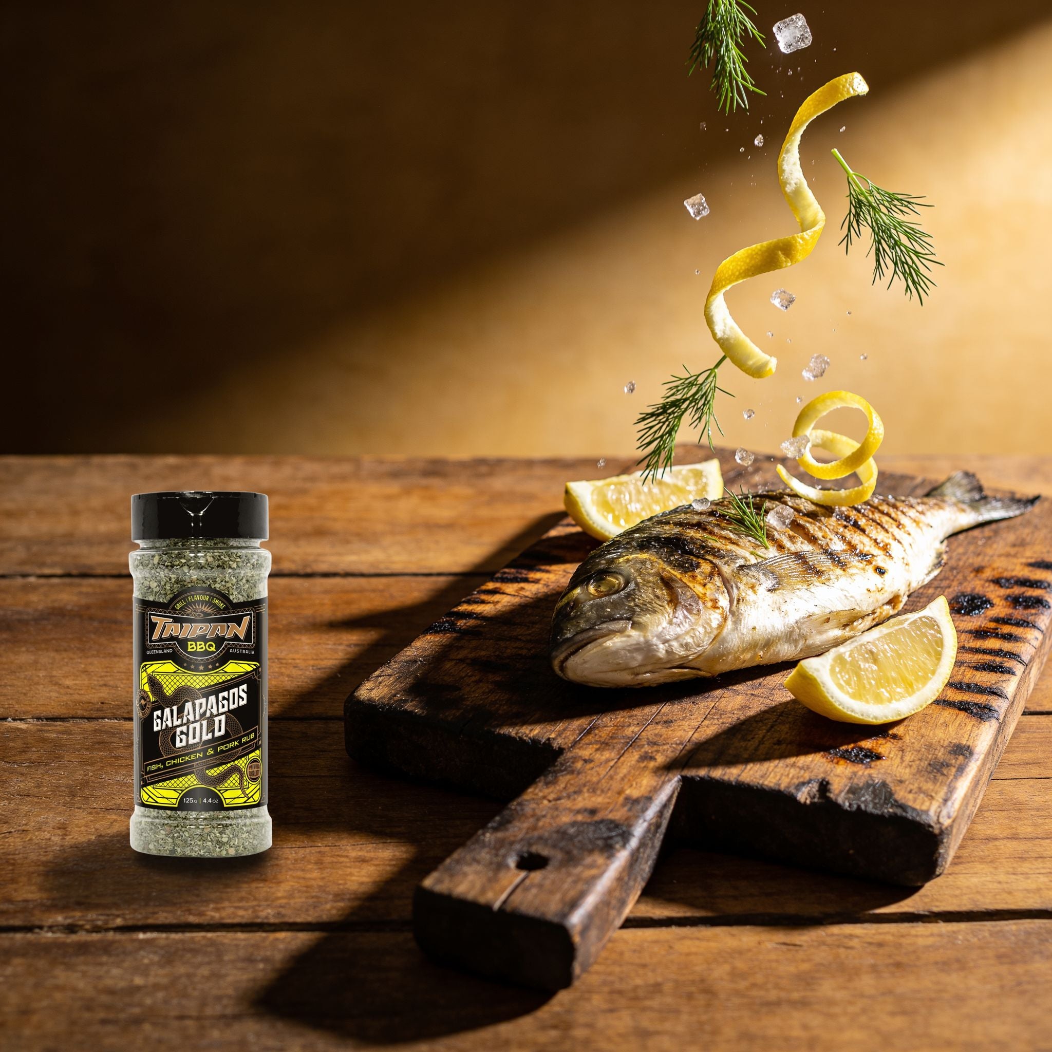 TAIPAN BBQ Galapagos Gold fish & seafood rub 125g — action shot, herb and lemon zest scattering over a grilled fish fillet