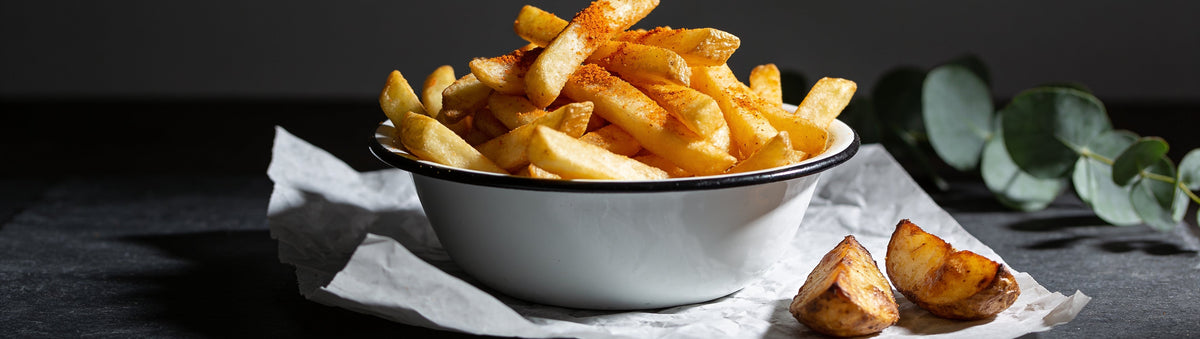 Bowl of seasoned golden hot chips and roast potato wedges on a dark slate bench – Taipan BBQ Kartoffen