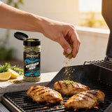 TAIPAN BBQ Mediterranean Magic chicken & fish rub 150g — in-use shot, rubbing seasoning onto chicken on the grill