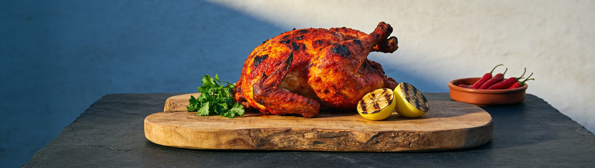 Charred peri-peri roast chicken with grilled lemons on a board – Taipan BBQ Portuguese Peri Peri rub