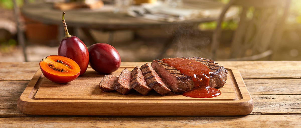 Tamco Tamarillo Relish 330g banner — sliced grilled steak topped with tamarillo relish and halved tamarillo fruit