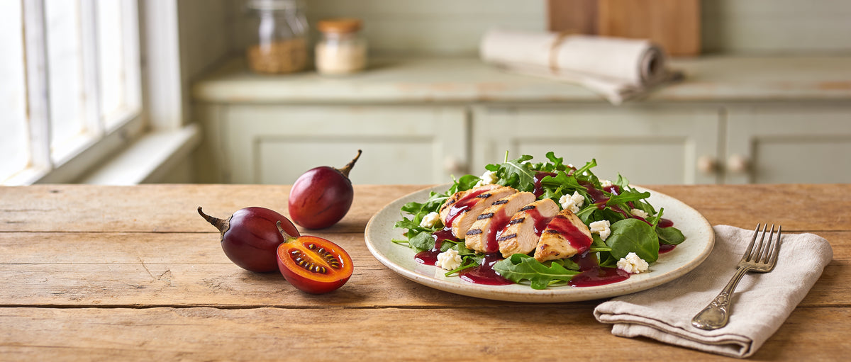 Tamco Tamarillo Vinaigrette banner — fresh green salad with grilled chicken and halved tamarillo fruit