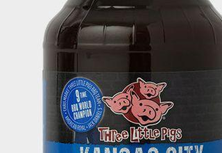 Three Little Pigs BBQ brand logo, three grinning pink pigs over a red disc, on transparent background