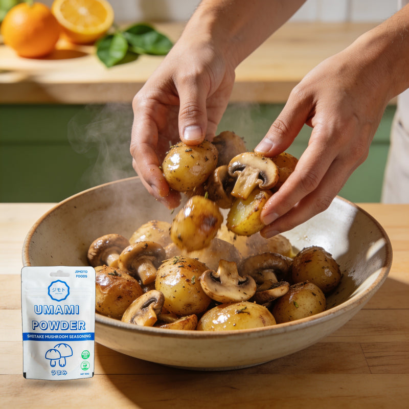 Jimoto Foods Umami Powder 80g Seasoning — hands tossing roasted potatoes and mushrooms in a steaming bowl beside the product pouch lifestyle photo