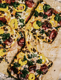 We the Pizza by Muhammad Abdul-Hadi hardback cookbook — interior page of square pizzas with pepperoni and greens